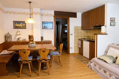 a kitchen and living room with a table and chairs at Casa a Penia-Alba a 2 minuti da impianti funivia in Penia