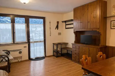 a living room with a television and a dining table at Casa a Penia-Alba a 2 minuti da impianti funivia in Penia