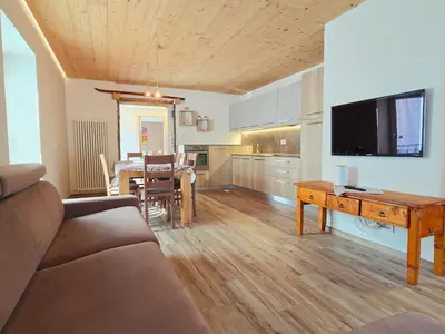 a living room with a couch and a table with a television at La Perla di Fassa - Alpine Stay Apartments in Moena