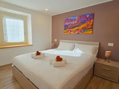a bedroom with a large white bed with two teddy bears on it at La Perla di Fassa - Alpine Stay Apartments in Moena