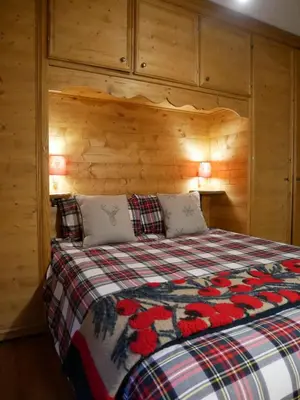 a bedroom with a bed with a wooden wall at Appartamento Val Di Roda in San Martino di Castrozza