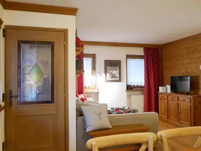 a living room with a couch and a table and a door at Appartamento Val Di Roda in San Martino di Castrozza