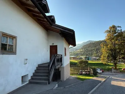 a building with a staircase leading to a door at Appartamento Centro del Fondo Lago di Tesero in Tesero