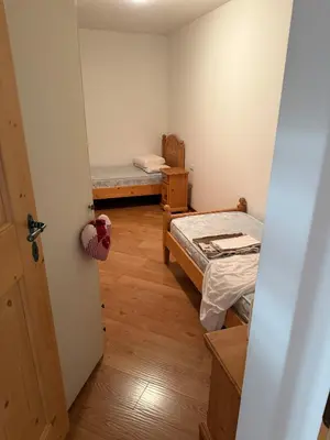 a small room with two beds and a door at Appartamento Centro del Fondo Lago di Tesero in Tesero
