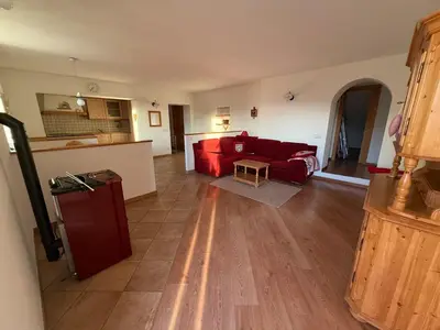 a living room with a red couch and a kitchen at Appartamento Centro del Fondo Lago di Tesero in Tesero