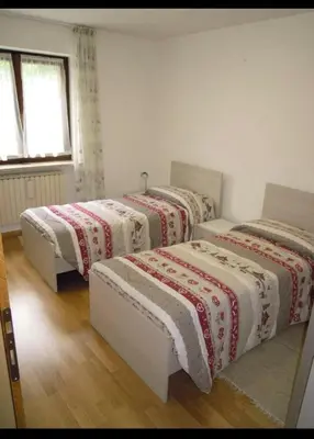 three beds in a room with white walls at Appartamento Rosa in Predazzo