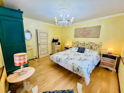 a bedroom with a bed and a table and a chandelier at Trilli House in Rocca Pietore