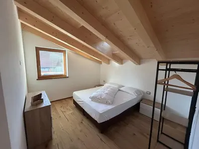 a small bedroom with a bed and a ladder at Lago House in Tesero