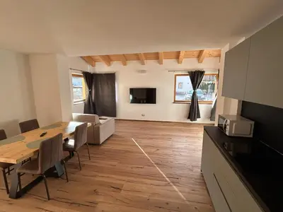 a kitchen and living room with a table and chairs at Lago House in Tesero