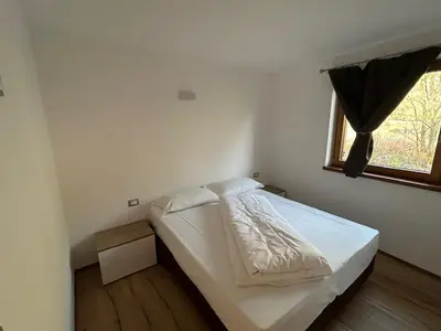 a small bedroom with a bed with a window at Lago House in Tesero