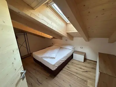 a bedroom with a bed in a small room at Lago House in Tesero