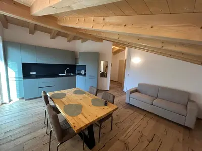 a kitchen and dining room with a table and a couch at Lago House in Tesero