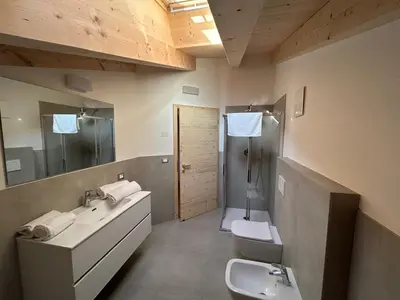 a bathroom with two sinks and a shower and a toilet at Lago House in Tesero
