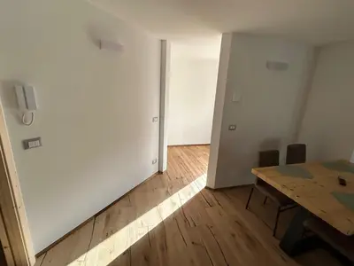 a room with a wooden table and a room with a white wall at Lago House in Tesero