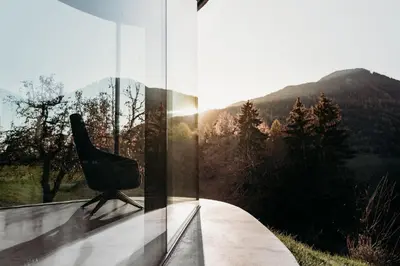 a chair sitting on a glass wall with a mountain view at Freiform Private Guesthouse in Chiusa