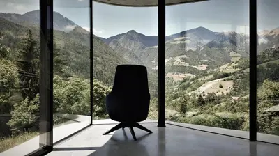 a chair in a room with a view of mountains at Freiform Private Guesthouse in Chiusa