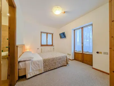 a bedroom with a large bed and wooden doors at Hotel Patri in Sottoguda