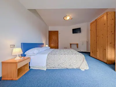 a bedroom with a large bed with two lamps at Hotel Patri in Sottoguda