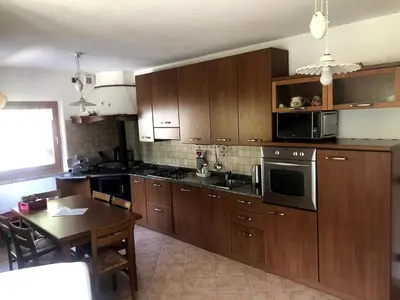 a kitchen with wooden cabinets and a table with a dining room at Fontanelle La Casa Dei Nonni in Elmo