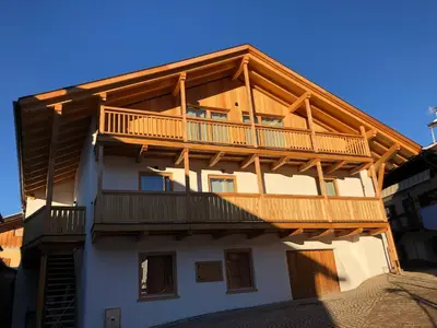 a wooden house with a balcony on top of it at Latemar Fiemme Apartments 1 in Tesero