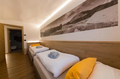 two beds in a room with a painting on the wall at Latemar Fiemme Apartments 1 in Tesero
