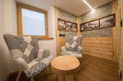 a living room with two chairs and a table at Latemar Fiemme Apartments 1 in Tesero