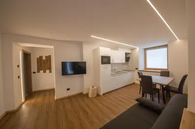 a living room with a dining table and a kitchen at Latemar Fiemme Apartments 1 in Tesero