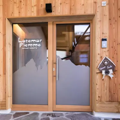 a glass door of a building with a sign on it at Latemar Fiemme Apartments 1 in Tesero