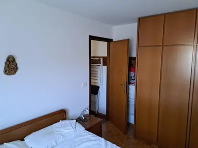 a bedroom with a bed and a closet and a refrigerator at Appartamento 8 Palazzina Maria in Ziano di Fiemme