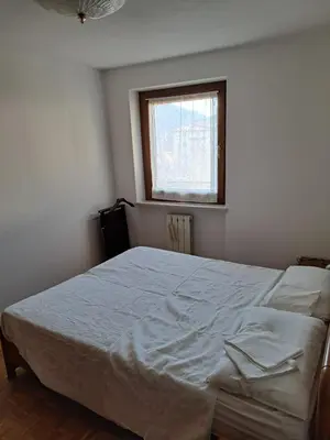 a bedroom with a white bed with a window at Appartamento 8 Palazzina Maria in Ziano di Fiemme