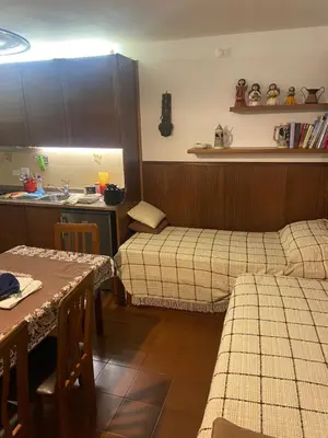 a small room with two beds and a kitchen at Appartamento 8 Palazzina Maria in Ziano di Fiemme