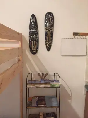 two masks hanging on a wall next to a shelf at Casa Similde e Casa Dolasilla in centro in Bolzano