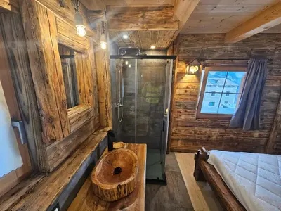 a bathroom with a wooden wall with a sink and a shower at Maso delle Falesie in Rocca Pietore