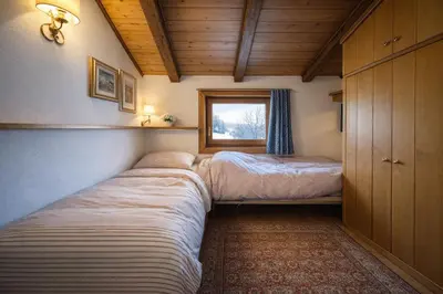 two beds in a small room with a window at Val di sopra - Panoramic attic in Cortina dʼAmpezzo