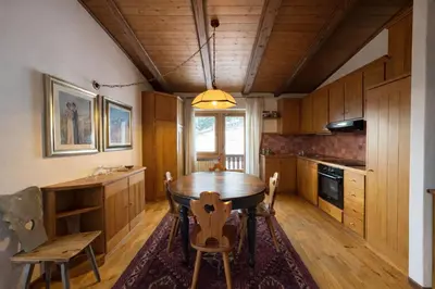 a kitchen with wooden cabinets and a wooden table and chairs at Val di sopra - Panoramic attic in Cortina dʼAmpezzo