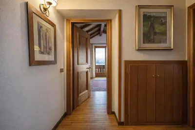 a hallway with a door and paintings on the walls at Val di sopra - Panoramic attic in Cortina dʼAmpezzo