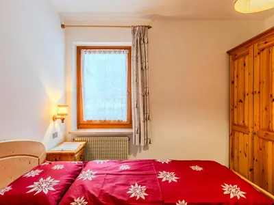 a bedroom with a red bed and a window at Apartment Cristina by Interhome in Campestrin