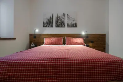 a red and white checkered bed in a bedroom at Dolomiapartments - Bosco Fontana 1 in Predazzo