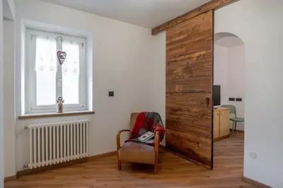 a room with a sliding door with a chair and a window at Dolomiapartments - Bosco Fontana 1 in Predazzo