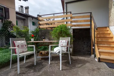 a patio with two chairs and a table and stairs at Dolomiapartments - Bosco Fontana 1 in Predazzo