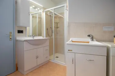 a white bathroom with two sinks and a shower at Dolomiapartments - Bosco Fontana 1 in Predazzo