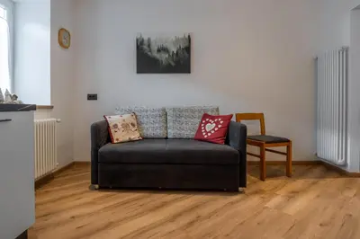 a living room with a couch and a chair at Dolomiapartments - Bosco Fontana 1 in Predazzo