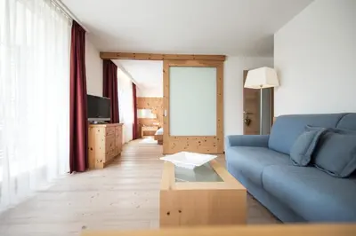 a living room with a blue couch and a table at Alpine Hotel Ciasa Lara in La Villa