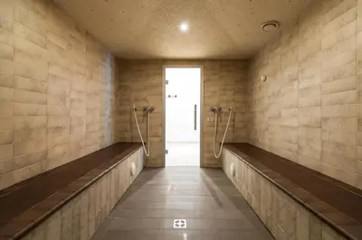 a bathroom with two benches and a door at Alpine Hotel Ciasa Lara in La Villa
