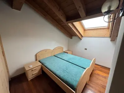 a bedroom with a bed with a wooden headboard and a window at Appartamento Al Settimo Cielo in Tesero