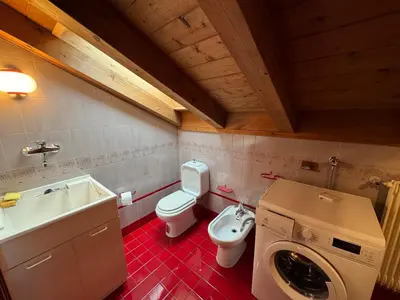 a bathroom with a toilet sink and a washing machine at Appartamento Al Settimo Cielo in Tesero