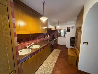 a large kitchen with two sinks and wooden cabinets at Appartamento Al Settimo Cielo in Tesero