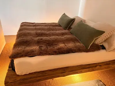 a bed with a brown blanket and pillows on it at Ca Costanza in Cortina dʼAmpezzo