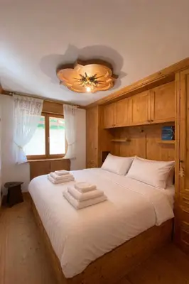a bedroom with a large white bed with a ceiling at Cortina Olympic Alpine Holidays in Cortina dʼAmpezzo