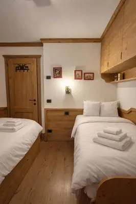 a bedroom with two beds with towels on them at Cortina Olympic Alpine Holidays in Cortina dʼAmpezzo
